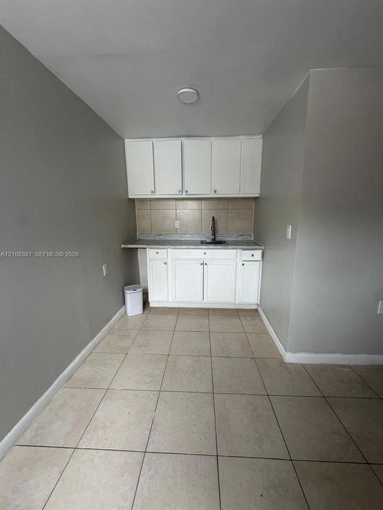 Kitchenette featuring white shaker-style cabinetry, neutral stone-finish countertops, ceramic tile backsplash, and ceramic tile flooring