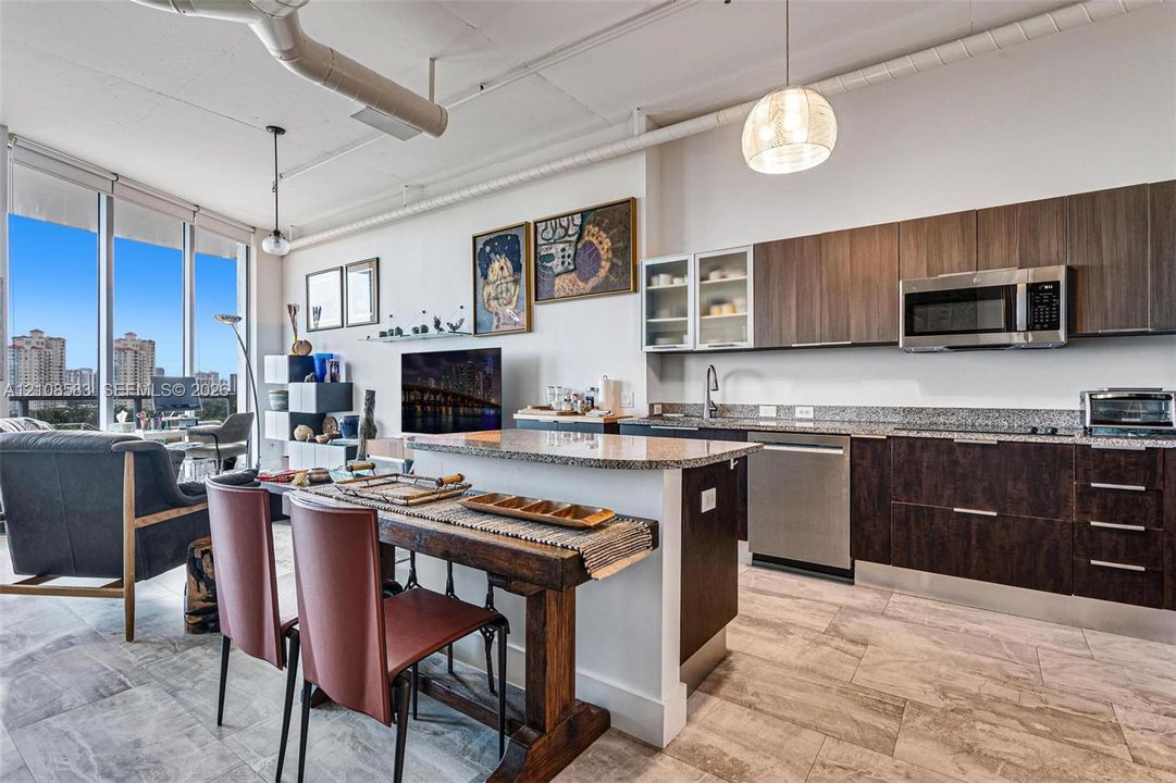 Contemporary kitchen featuring dark wood-finish cabinetry, stone countertops, stainless steel appliances, tile flooring, and floor-to-ceiling windows