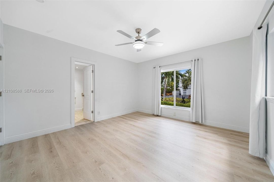 2nd Bedroom - Neutral-toned room featuring wood-finish flooring, a white ceiling fan with integrated lighting, and a large window