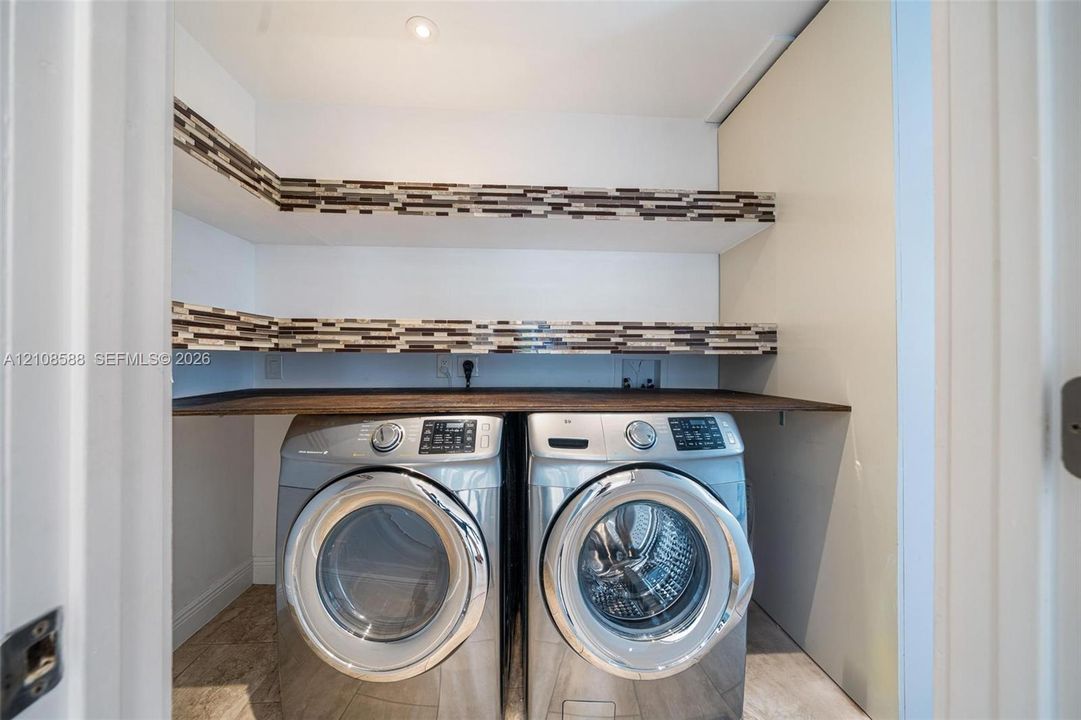 Laundry room featuring wood-finish countertop, dual-tier open shelving with mosaic tile backsplash, and recessed lighting