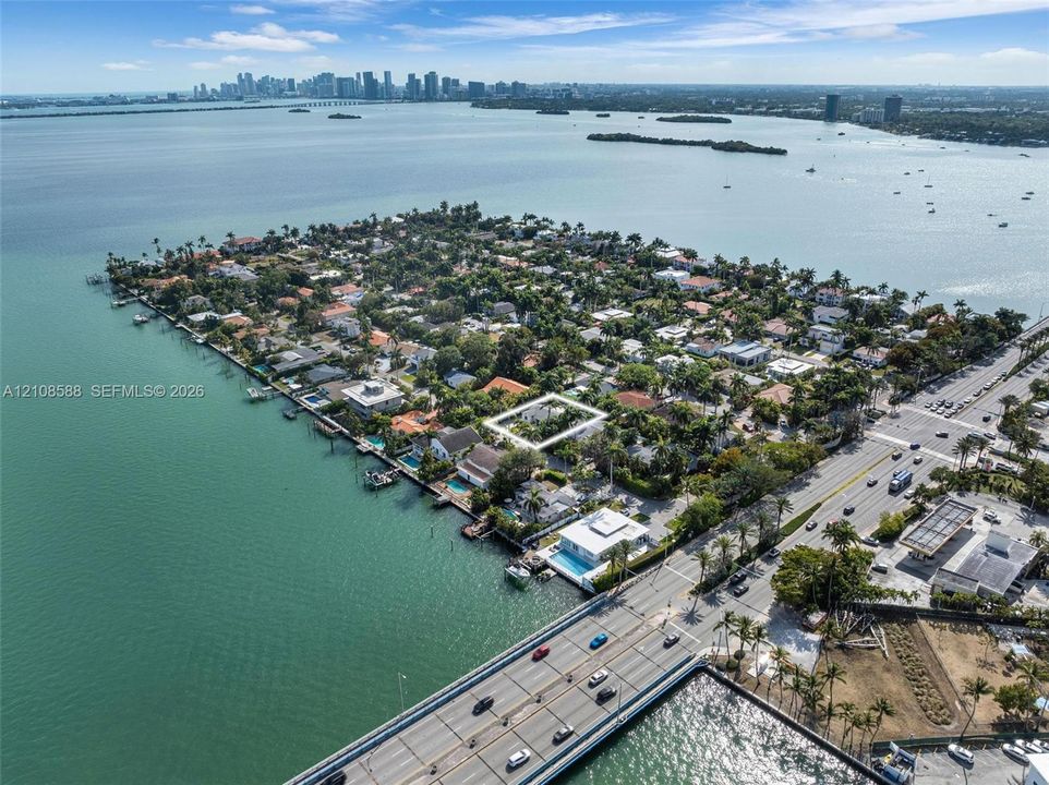 Aerial perspective of a residential parcel situated on a peninsula, characterized by mature tree canopy and proximity to coastal waters