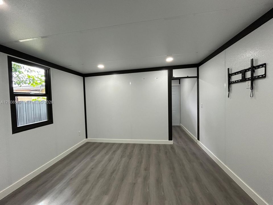 Interior room featuring wood-finish flooring, high-contrast black trim, recessed lighting, and a single-pane window