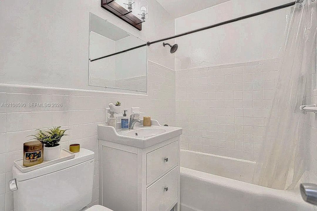 Bathroom featuring a white pedestal vanity with storage drawers, a recessed medicine cabinet, square wall tile surround, and a tub-shower combination with a showerhead