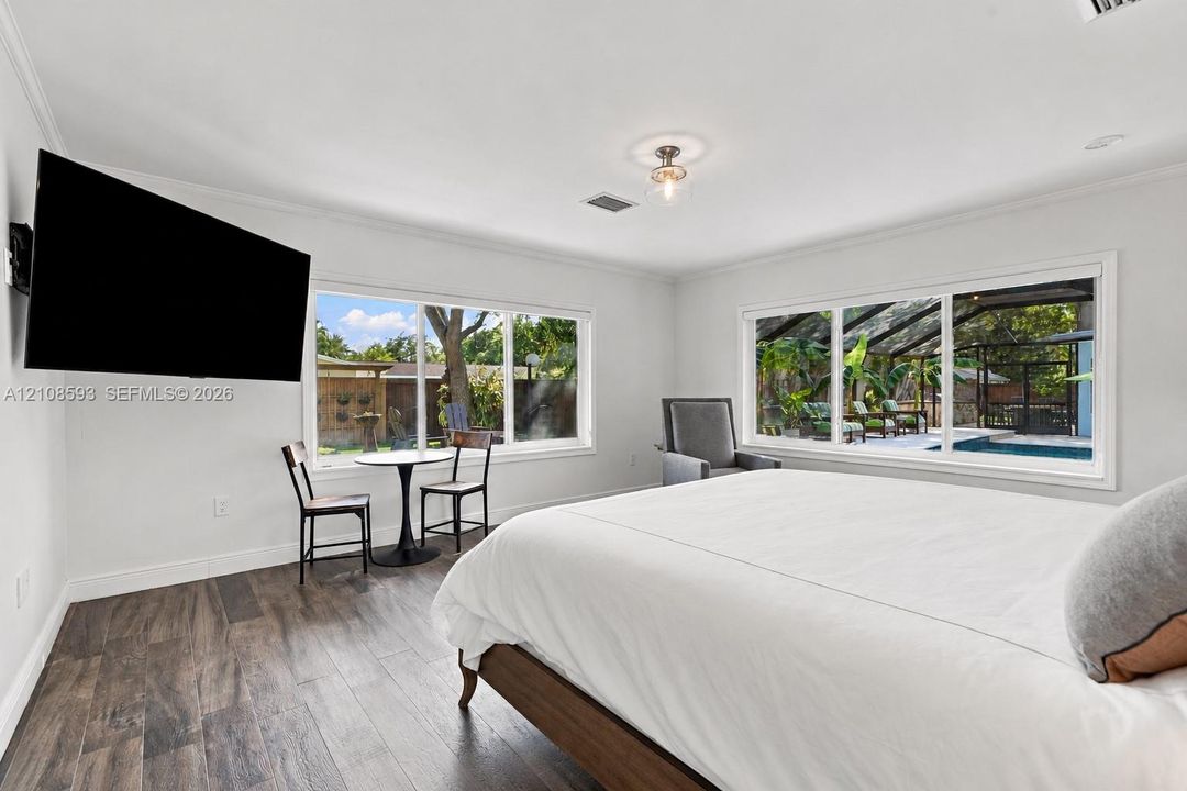 Neutral-toned interior featuring wood-finish flooring, dual large-scale windows with natural light, a semi-flush mount ceiling fixture, and crown molding