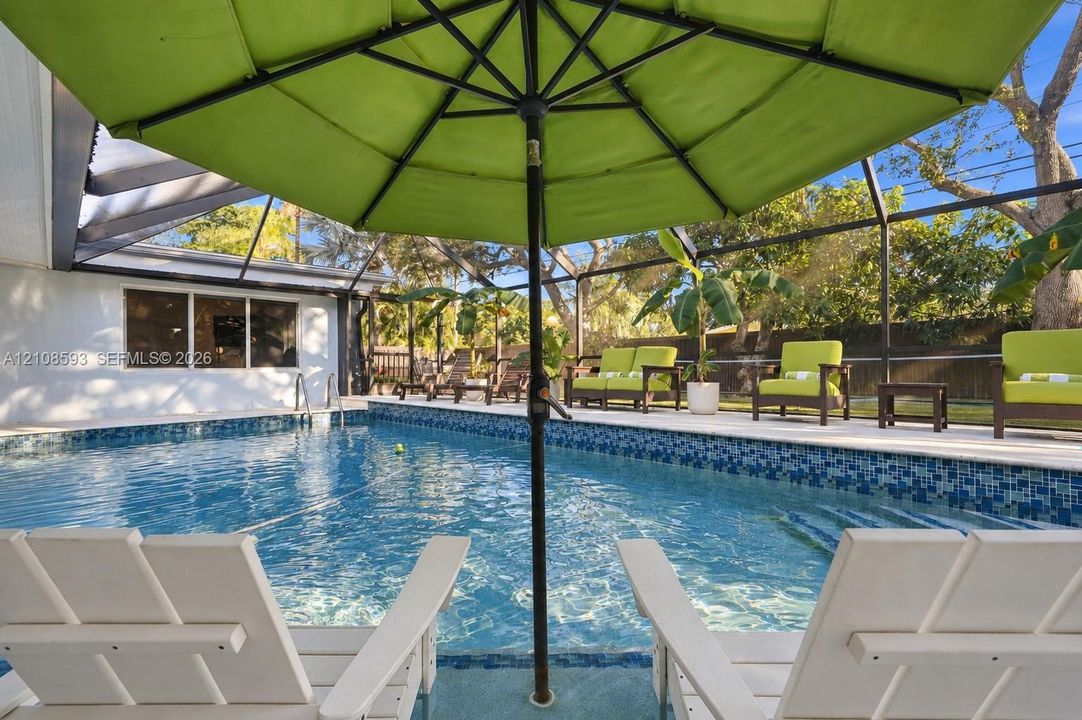 Screened-in patio area featuring a swimming pool with blue mosaic tile perimeter and concrete pool deck