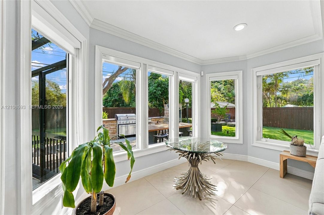Sunroom featuring large paneled windows, neutral tile flooring, crown molding, and recessed lighting