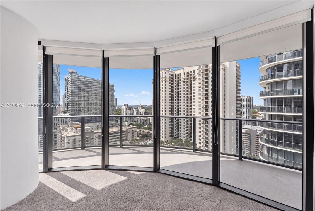 Curved balcony with glass railing, floor-to-ceiling windows, and wall-to-wall carpeting