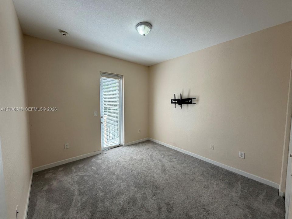 Room featuring wall-to-wall carpeting, neutral paint, a single-light flush mount ceiling fixture, and a glass-paneled door with integrated blinds