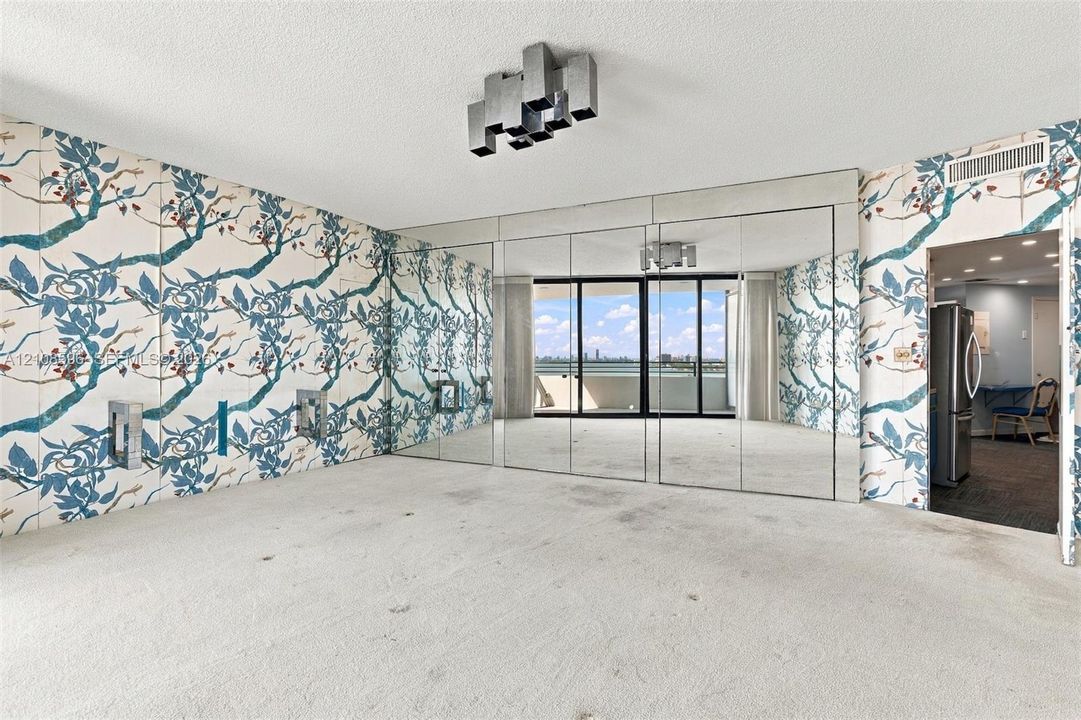 Living area featuring floor-to-ceiling mirrored wall panels, patterned wallpaper, a structural sliding glass door, and a geometric ceiling-mounted light fixture