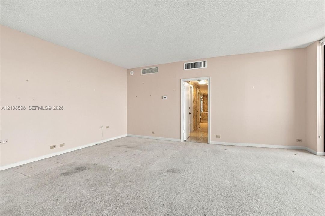 Expansive interior room featuring neutral wall finishes, plush carpeting, and recessed ceiling HVAC registers