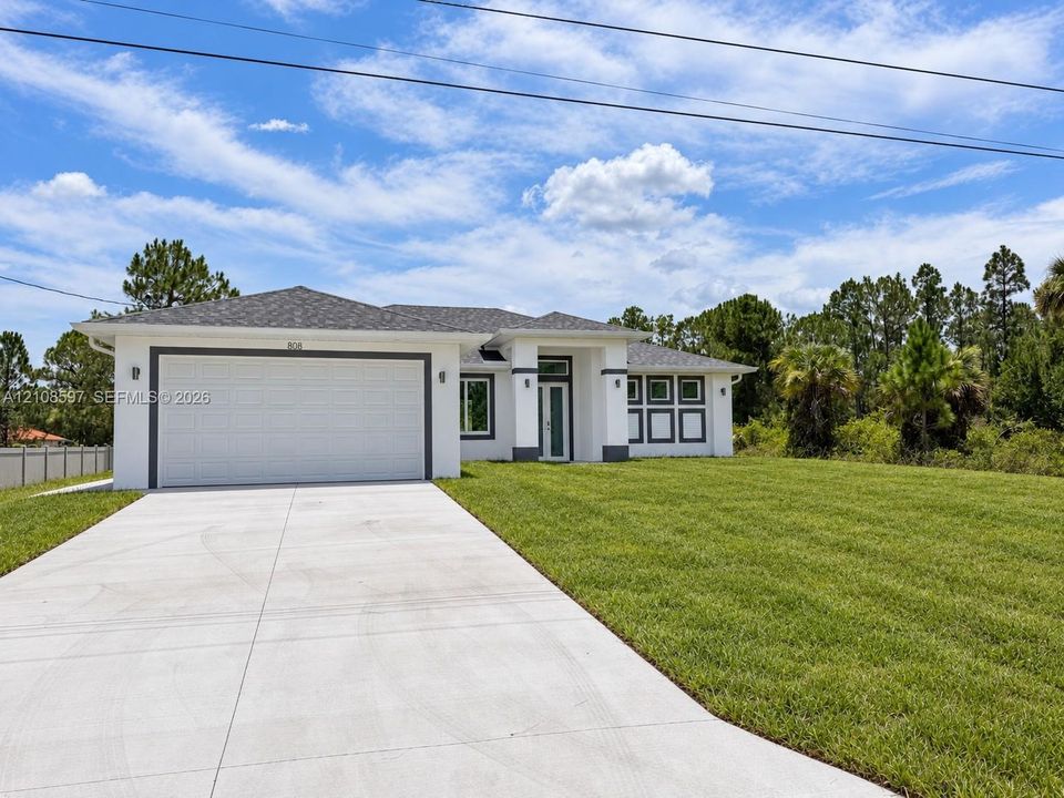 Single-story exterior featuring white stucco siding, a grey shingled hip roof, a concrete driveway, and an attached two-car garage