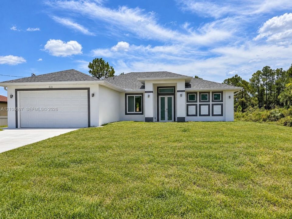 Stucco exterior featuring a dual-car garage, recessed entryway with a glass-paneled front door, transom window, and architectural shingle roofing