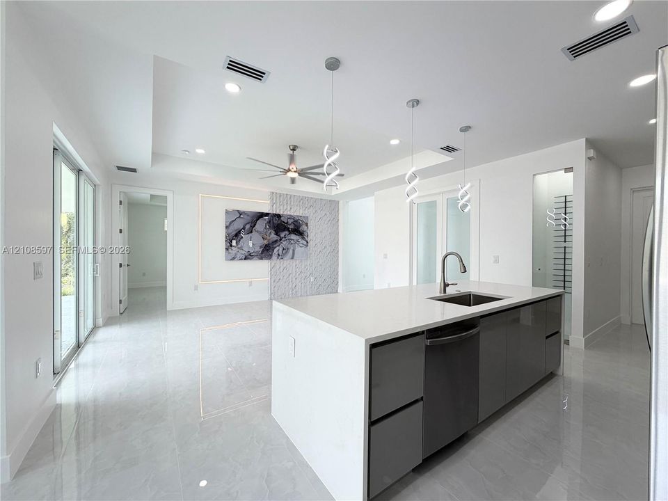 Kitchen island featuring a stone-composite countertop, undermount sink, and high-gloss cabinetry