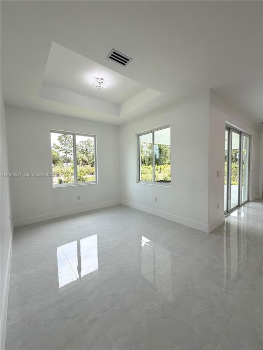 Tray ceiling featuring a modern light fixture, large-format polished tile flooring, and sliding glass doors