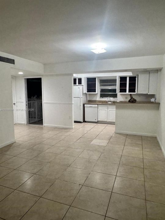 Kitchen featuring white shaker-style cabinetry, a breakfast bar, and tile flooring