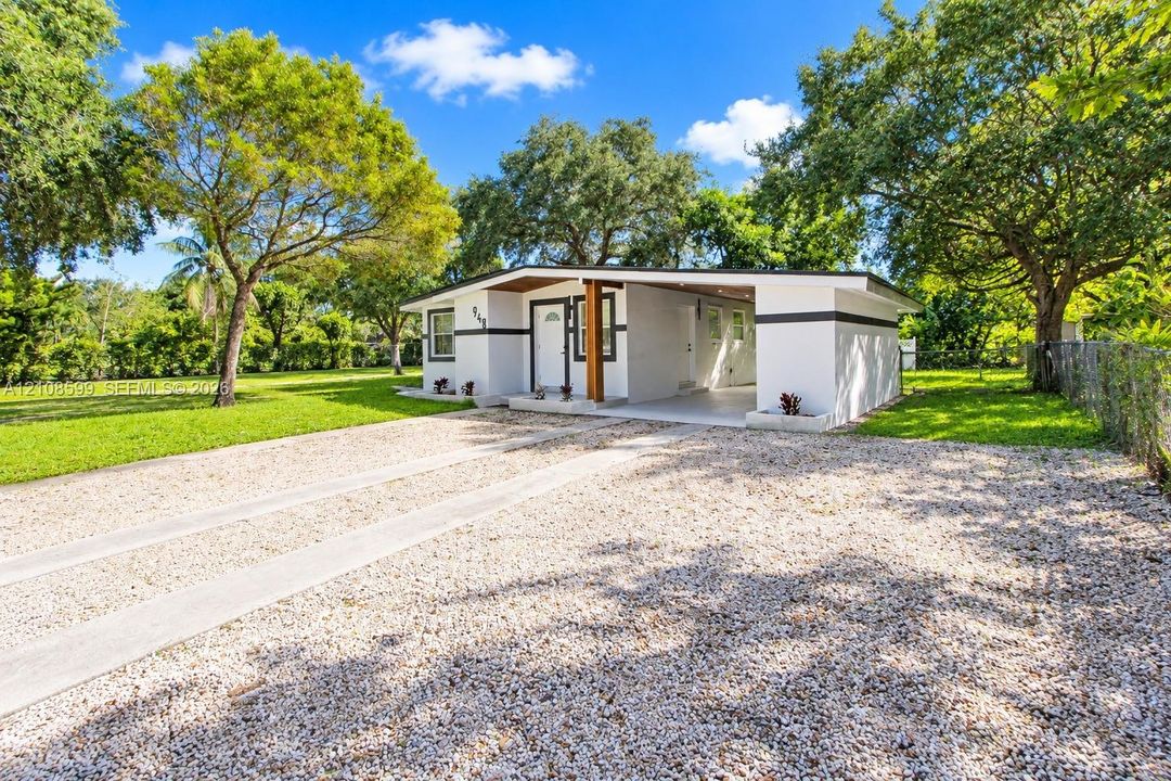 Single-story residence featuring a mid-century modern aesthetic, stucco exterior, integrated carport, concrete driveway, and mature landscaping