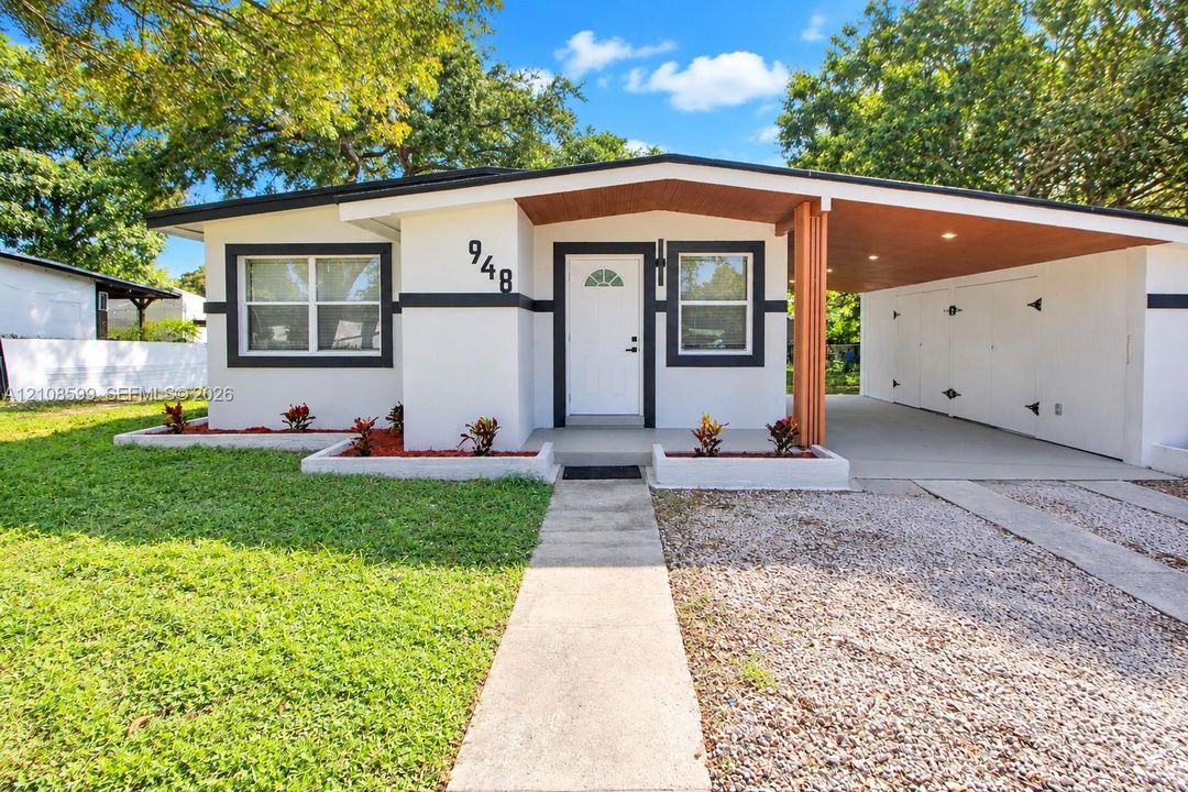 Mid-century exterior featuring a recessed entry, covered carport, wood-paneled ceiling, concrete walkway, and raised planting beds