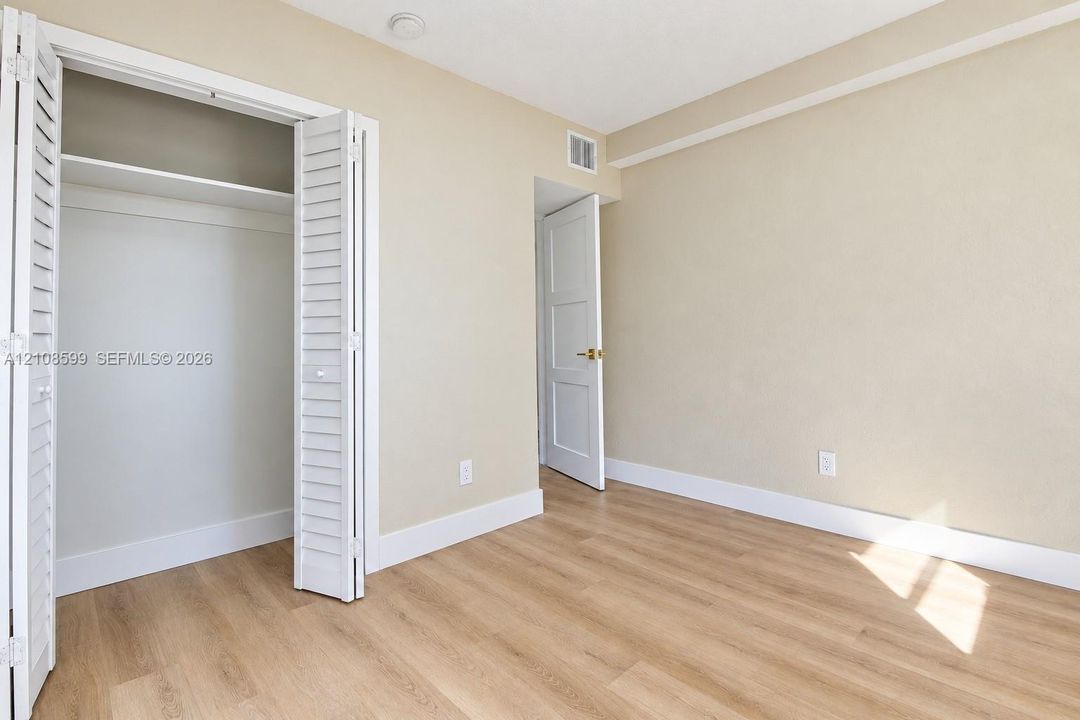 Interior space featuring wood-finish flooring, a closet with louvered bi-fold doors, and a paneled interior door with gold-tone hardware