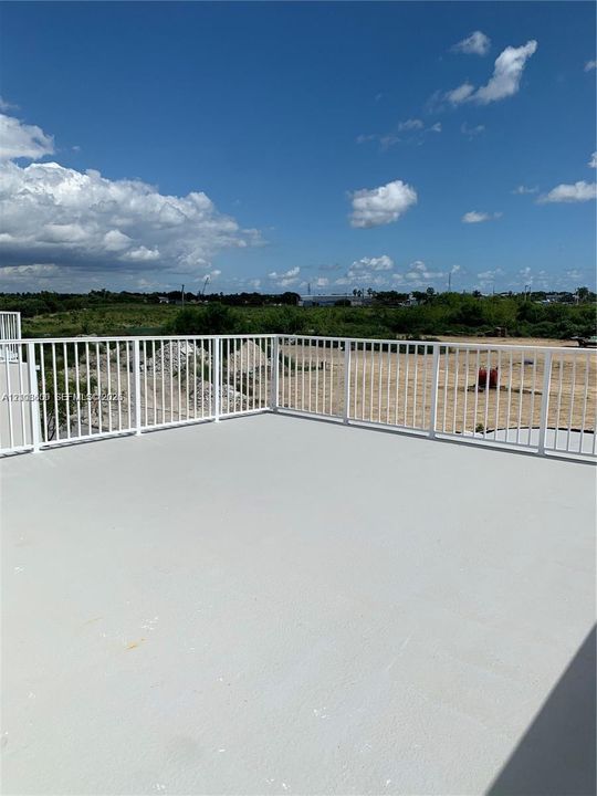 Open-air terrace featuring a concrete floor surface and white metal railing