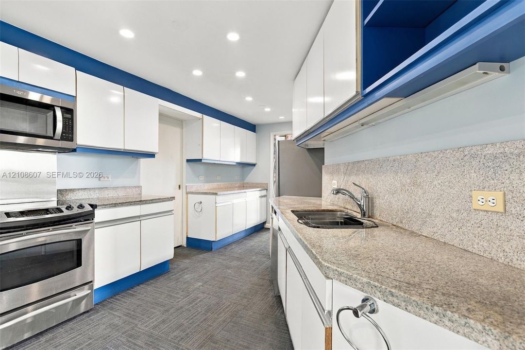 Kitchen featuring white cabinetry, stone-finish countertops, stainless steel appliances, recessed ceiling lighting, and hard-surface flooring