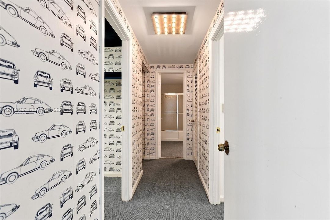 Hallway featuring patterned wallpaper, flush-mount grid lighting, and wall-to-wall carpeting