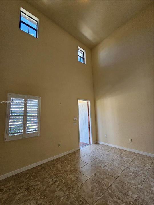 High-volume ceilings with two levels of windows, tile flooring, and interior window shutters