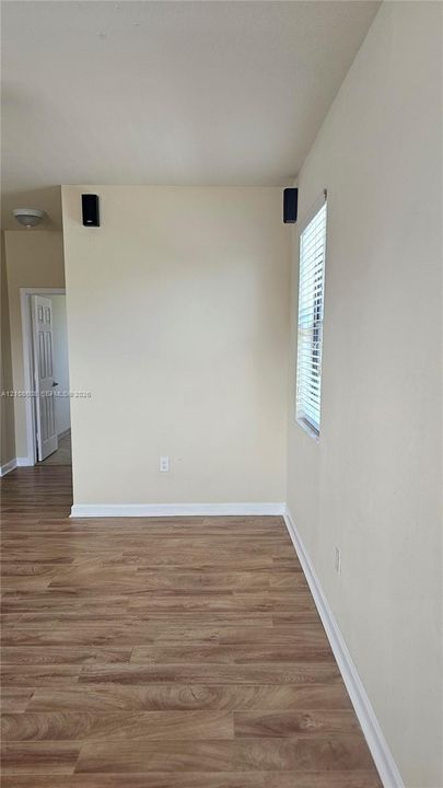 Interior space featuring wood-finish flooring, a neutral wall palette, and a window with horizontal blinds
