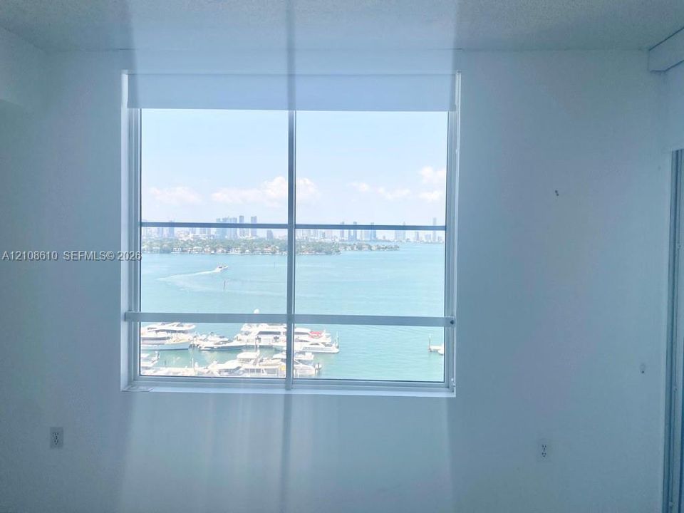 Large picture window with metal frame featuring an expanse of water, marina, and city skyline