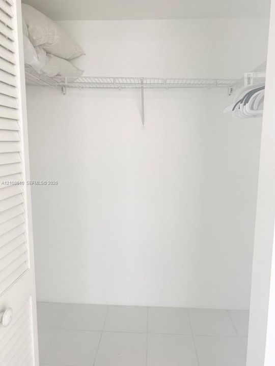 Closet featuring white louvered doors, wire shelving, and tile flooring
