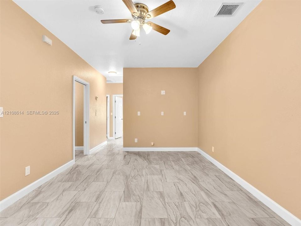 Interior space featuring wood-finish flooring, neutral wall tones, and a ceiling fan with integrated light fixtures