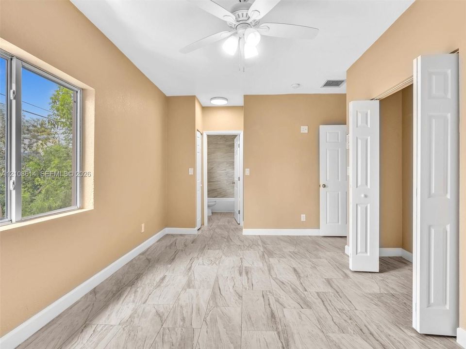 Room featuring wood-finish flooring, a multi-blade ceiling fan with integrated lighting, a sliding closet door, and dual interior doors