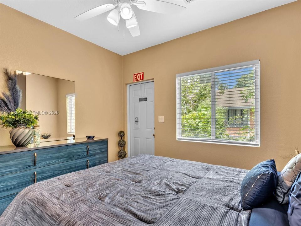 Bedroom featuring a ceiling fan with integrated lighting and a large window with horizontal blinds
