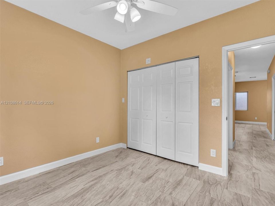Room featuring wood-finish flooring, a white three-blade ceiling fan with integrated light fixture, and a white bifold closet door