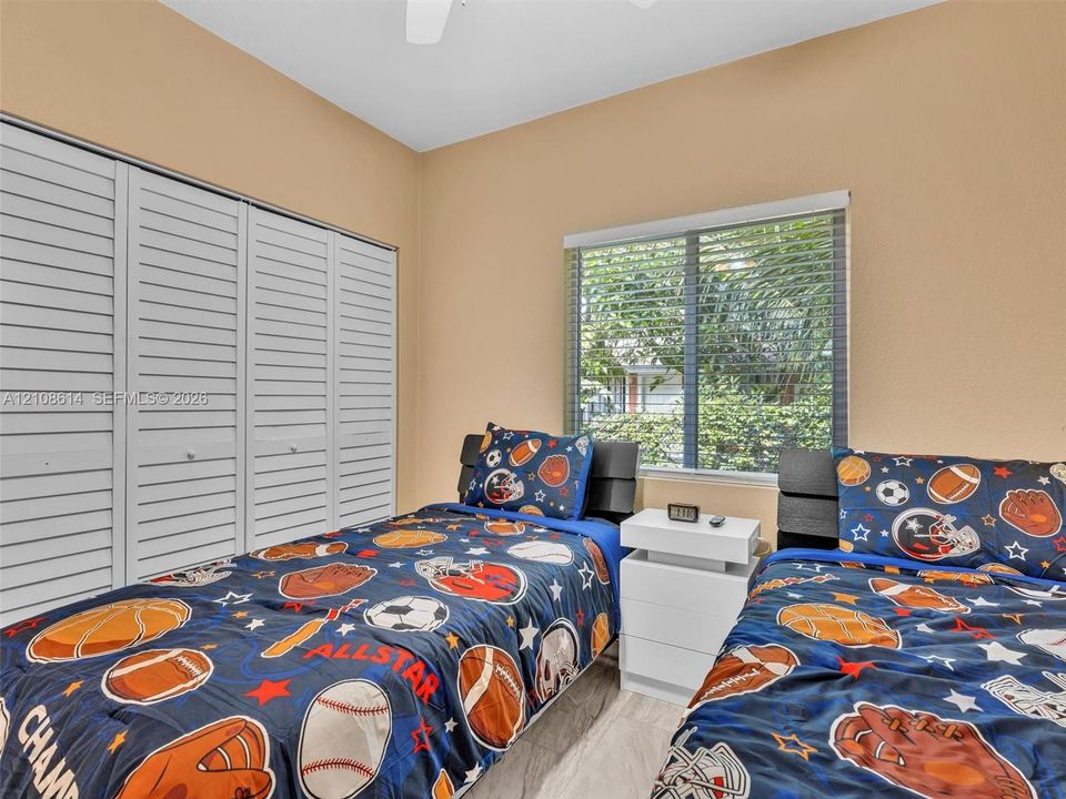 Room featuring louvered bi-fold closet doors, horizontal window blinds, and light-toned flooring