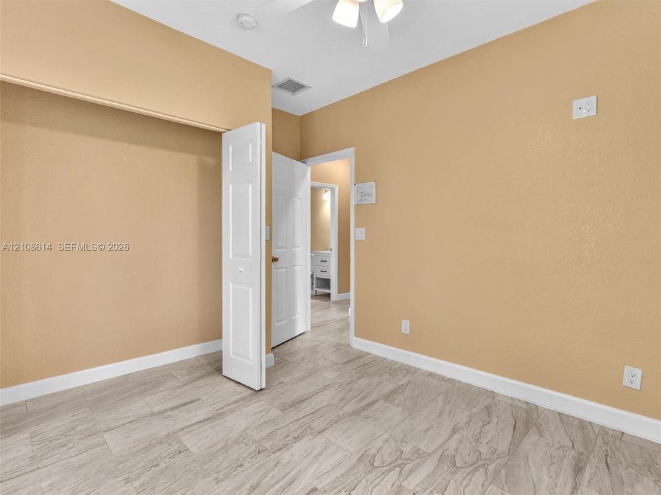 Neutral-toned interior space featuring light-colored wood-finish flooring, a bi-fold closet door, and a ceiling-mounted light fixture