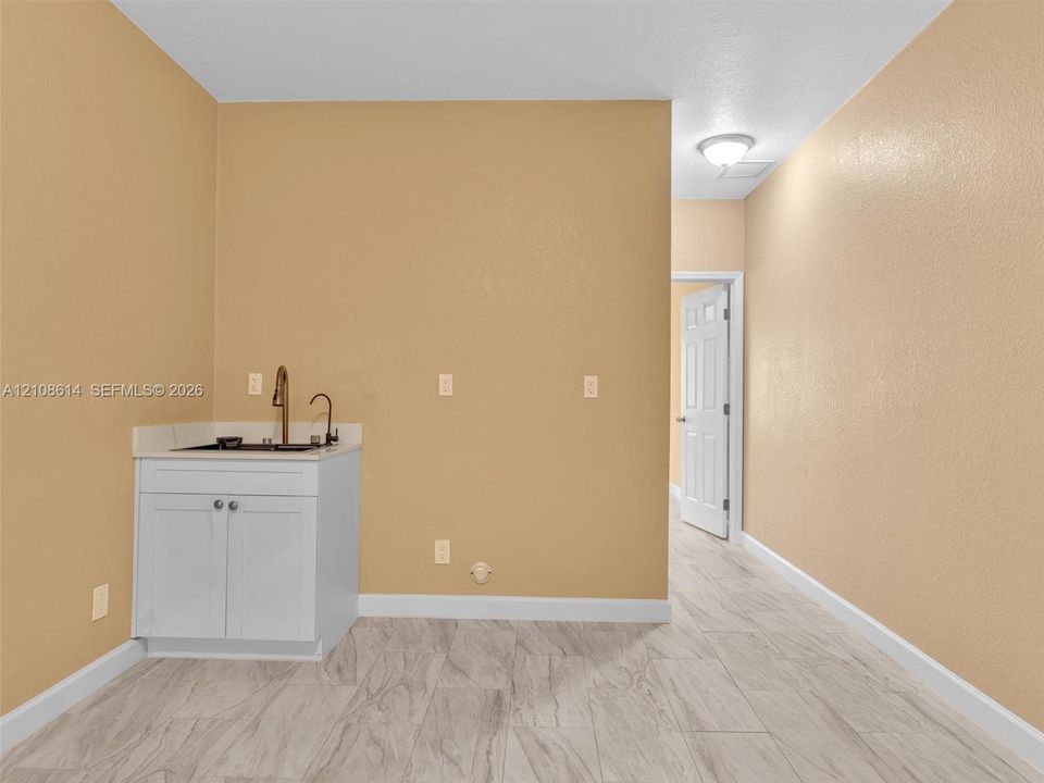 Built-in white vanity featuring a stone countertop, an integrated sink with a tall gooseneck faucet, and light wood-finish flooring