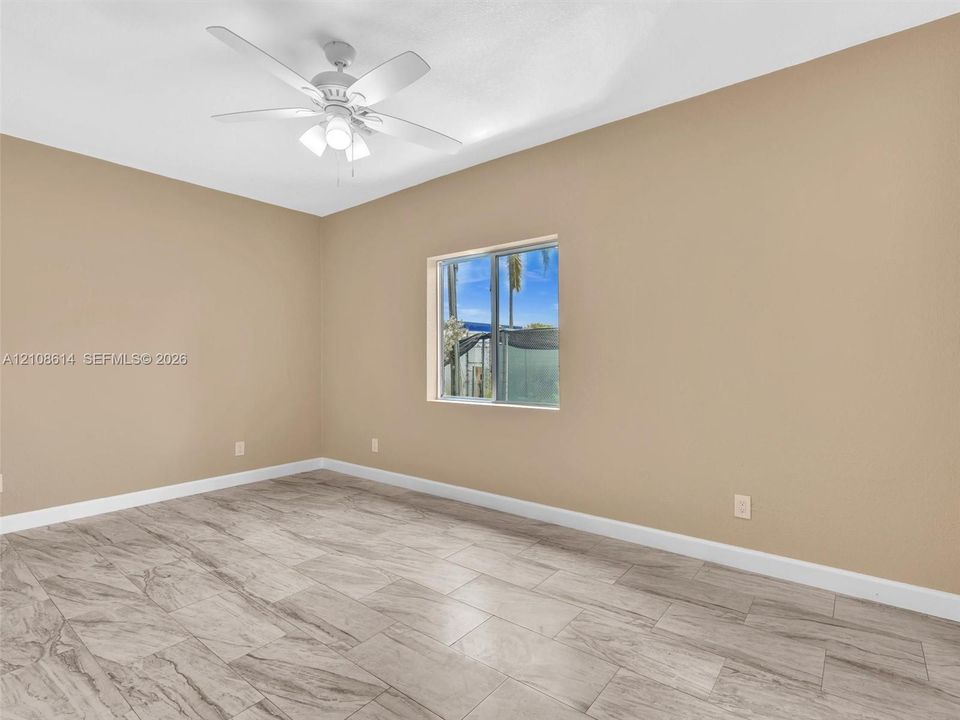 Room featuring neutral-toned walls, wood-finish tile flooring, a white ceiling fan with integrated lighting, and a window with a horizontal sliding pane