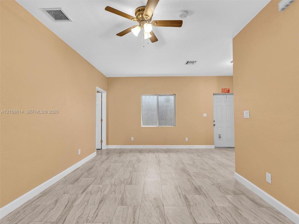 Interior space featuring wood-finish tile flooring, a neutral wall palette, a multi-blade ceiling fan with integrated lighting, and a single sliding window