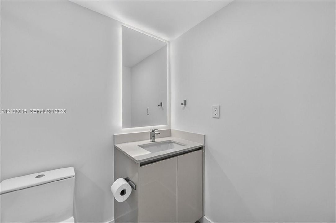 Modern vanity with a countertop basin, LED-backlit mirror, and chrome faucet fixture