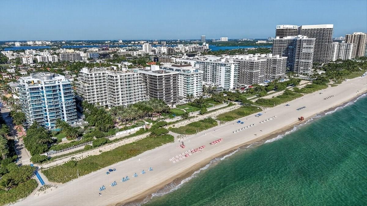 Aerial perspective of waterfront high-rise development featuring direct beach access, coastal shoreline, and proximity to regional urban infrastructure