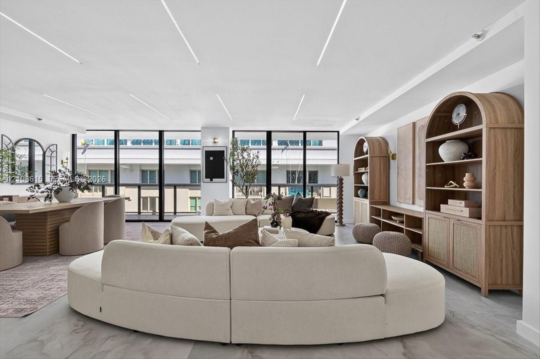 Floor-to-ceiling windows, recessed linear ceiling lighting, built-in arched wood cabinetry, and large-format tile flooring