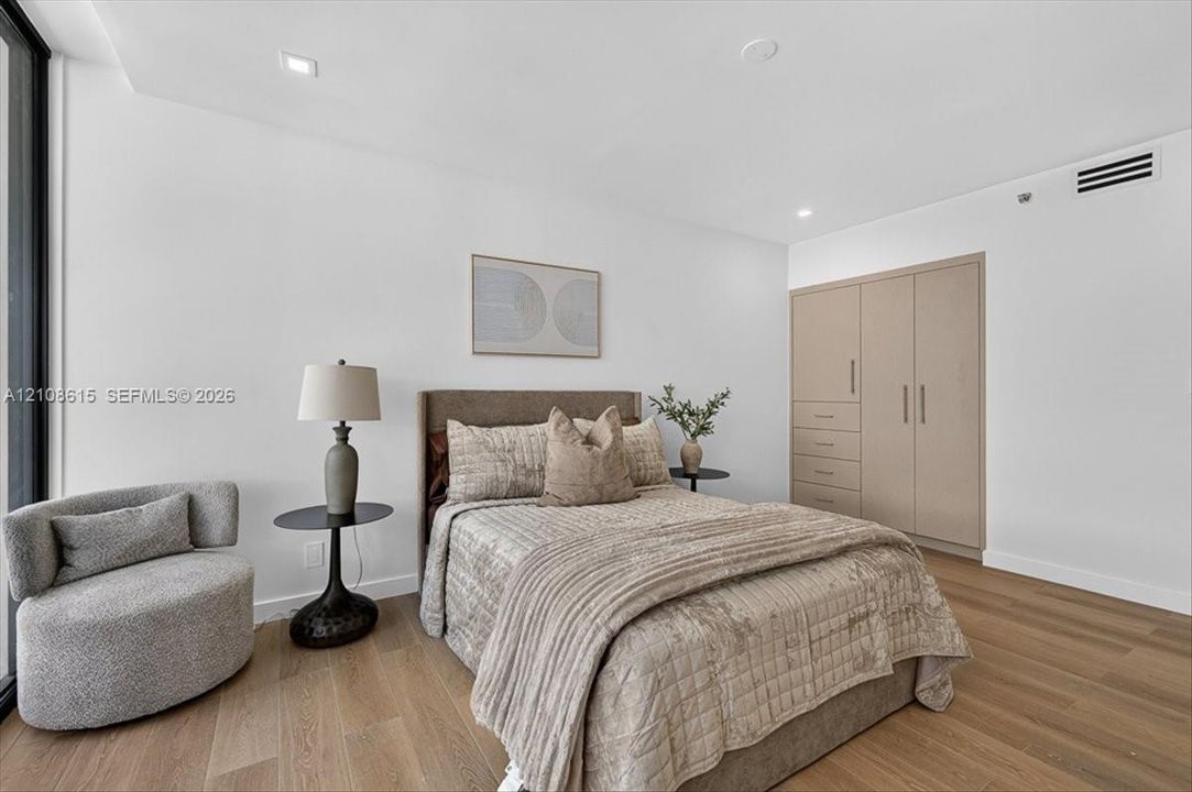 Bedroom featuring wood-finish flooring, recessed lighting, and floor-to-ceiling built-in cabinetry with integrated drawer storage