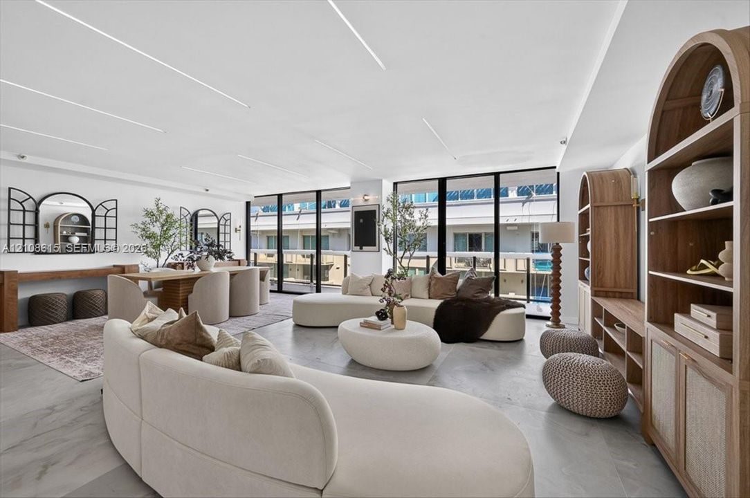 Open-concept interior featuring large-format tile flooring, floor-to-ceiling windows, custom built-in arched cabinetry, and recessed linear ceiling lighting