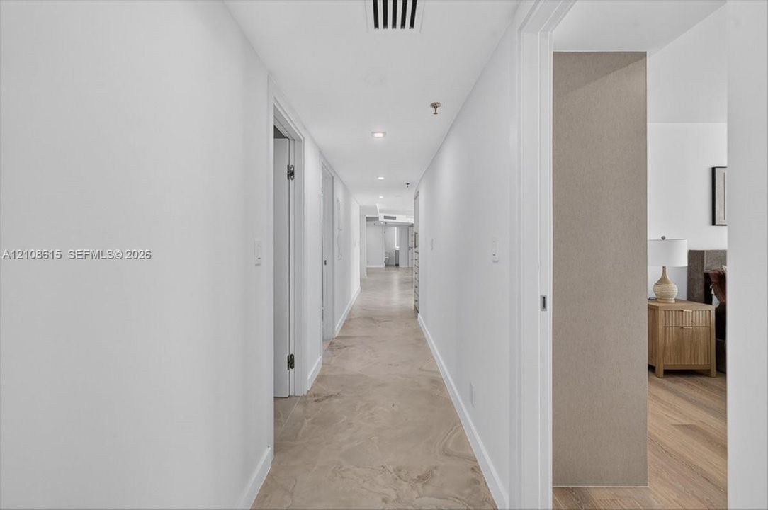 Hallway featuring stone-finish tile flooring, recessed ceiling lighting, and neutral wall tones
