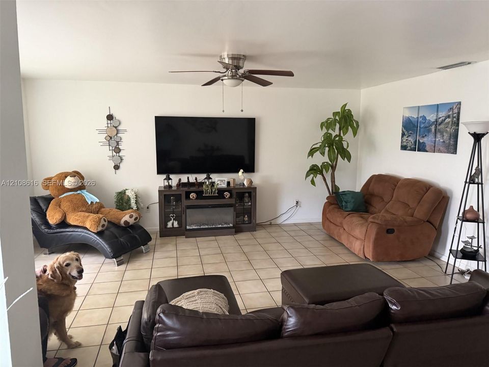 Living area featuring tile flooring, ceiling fan, and built-in electric fireplace console
