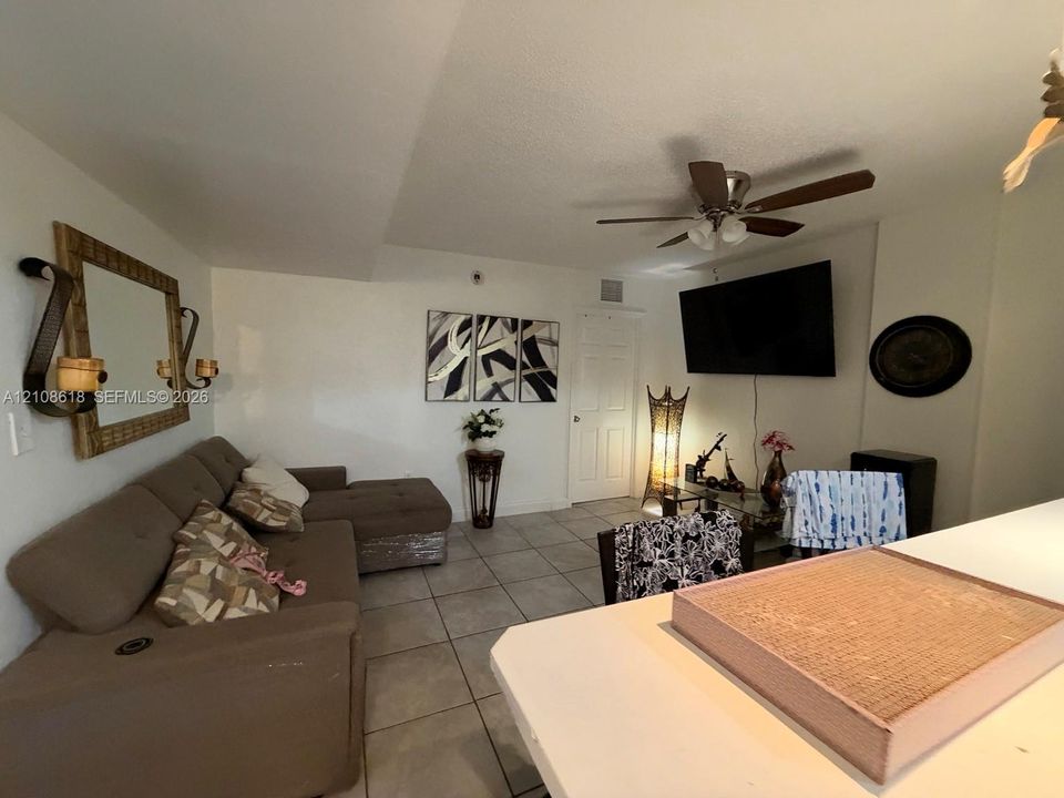 Large-format tile flooring, ceiling fan with integrated lighting, and white interior doors