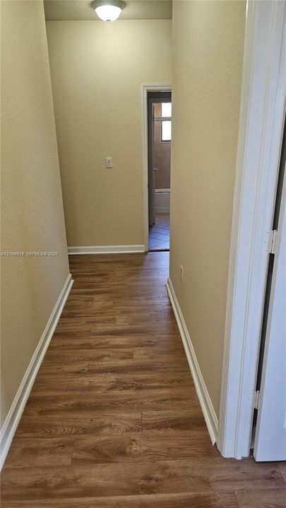 Hallway featuring wood-finish flooring, neutral-toned walls, and a flush-mount ceiling light fixture