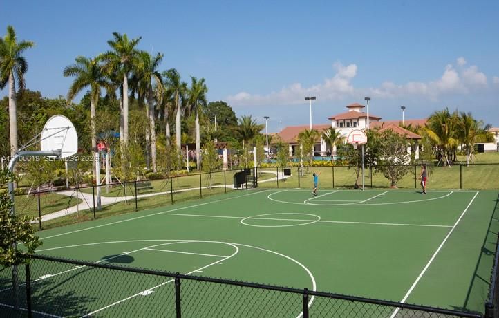 Outdoor basketball court with chain-link fencing, manicured landscaping, paved pathways, and clubhouse access