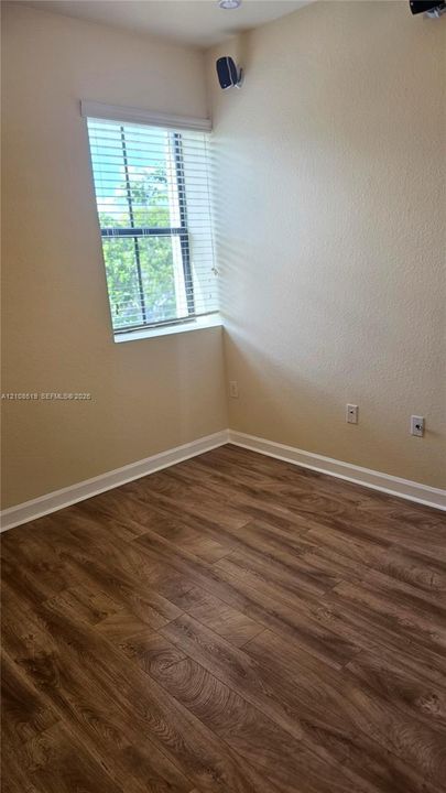 Interior room featuring wood-finish flooring, a single-hung window with horizontal blinds, neutral wall paint, and recessed lighting