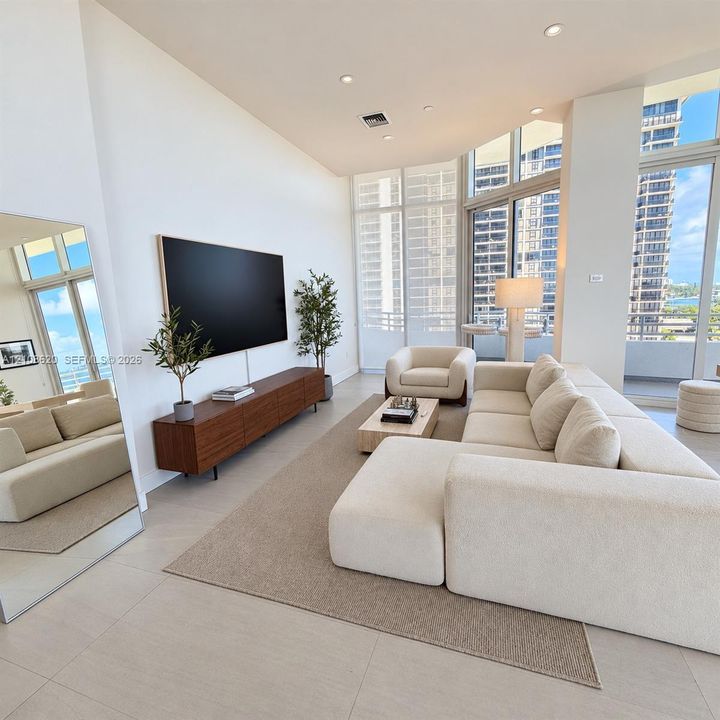 Vaulted ceilings, expansive floor-to-ceiling windows, light-toned tile flooring, and integrated recessed lighting